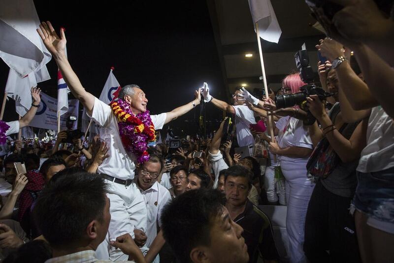 Top, Lee Hsien Loong, Singapore’s prime minister and the leader of the People’s Action Party, celebrates after its landslide election win earlier this month. Above, his father, Prime Minister Lee Kuan Yew, visits the newly built Commonwealth Close Estate in 1965. Nicky Loh / Bloombeg