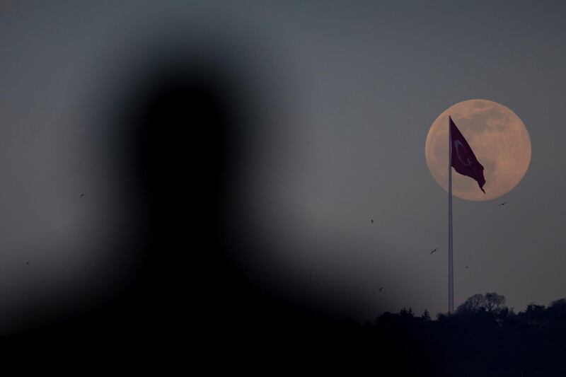 A man watches on as an almost full pink supermoon rises over Istanbul in Istanbul, Turkey. Getty Images