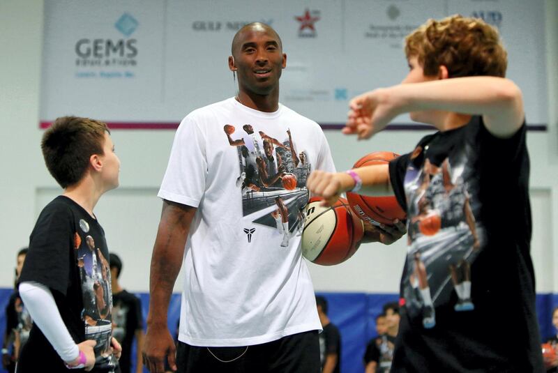 Students of Gems American Academy in Abu Dhabi looks at LA Lakers NBA basketball player Kobe Bryant (C) during a training session on September, 26, 2013. Bryant arrived for a Health and Fitness Weekend, to promote awareness of diabetes in the United Arab Emirates in his first trip to a Middle East country.          AFP PHOTO/MARWAN NAAMANI (Photo by MARWAN NAAMANI / AFP)