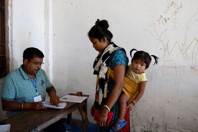 A woman from the Toto tribe, carrying her daughter, gets her name checked in a voters list at a polling station during the first phase of general election, in Alipurduar district in the eastern state of West Bengal, India. Reuters