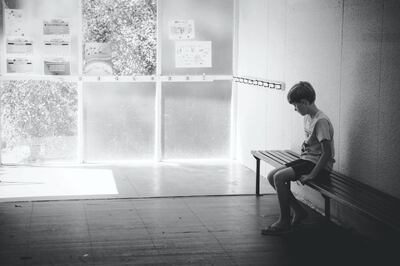 A young boy sits outside at school.