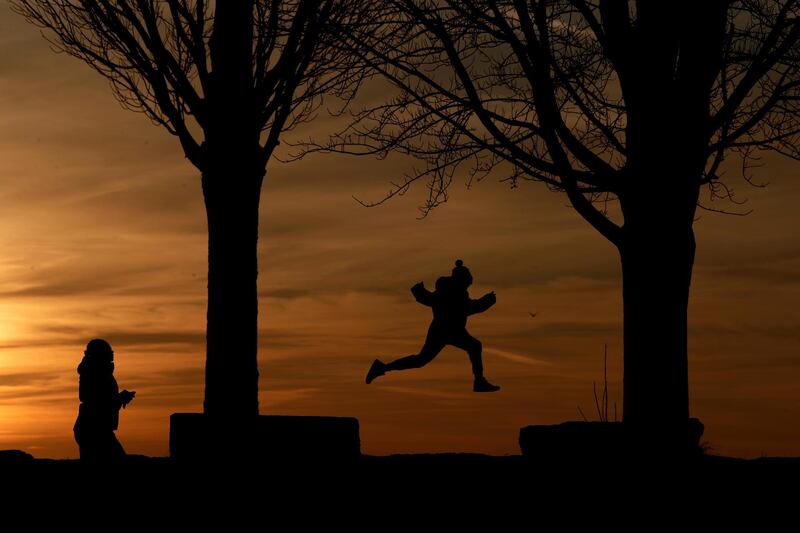 A child leaps between rock platforms as a woman walks behind him as the sun sets behind Lake Erie at the Erie Basin Marina in Buffalo, New York. Julio Cortez / AP Photo