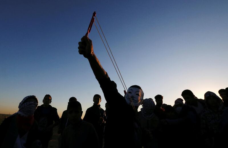 A Palestinian demonstrator uses a slingshot to hurl stones at Israeli troops during a protest at the Israel-Gaza border fence. Reuters