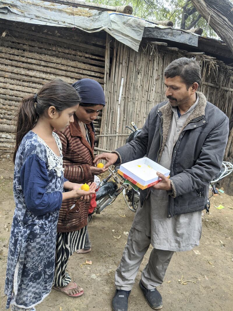 Dharam Veer Solanki, the leader of the Pakistani Hindu community in Majnu Ka Tilla in New Delhi distributing sweets to children. Taniya Dutta for The National