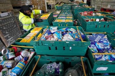 A volunteer collects food at a storage centre in London. Across Britain, food banks and community food hubs are helping struggling families through a cost-of-living crisis. AP