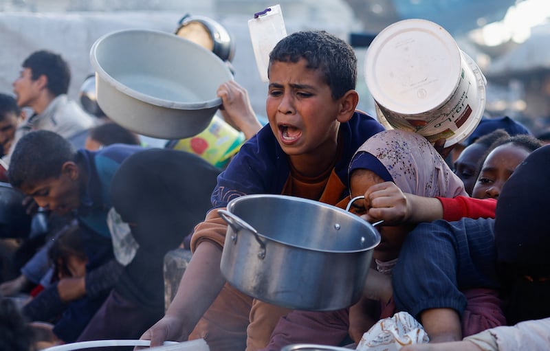 Children wait to receive food in Rafah. The UN has warned that many in Gaza are facing famine. Reuters