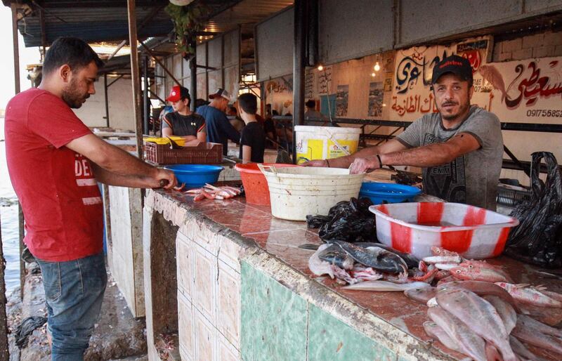 Vendors clean fish for costumers at a fish market in the eastern Libyan port city of Benghazi during the last week of the Muslim fasting month of Ramadan.   AFP