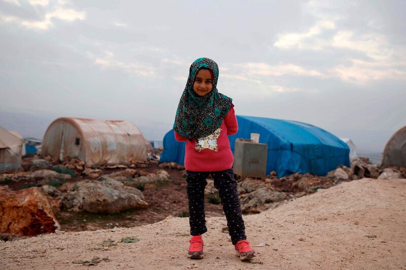 TOPSHOT - Syrian Maya Merhi poses for a picture in the Internally Displaced Persons (IDP) camp of Serjilla in northwestern Syria next to Bab al-Hawa border crossing with Turkey, on December 9, 2018. Eight-year-old Maya, born with no legs due to a congenital condition, had to struggle around the Syrian camp on artificial limbs made of plastic tubing and tin cans. Today, the girl can walk thanks to her new prosthetics after undergoing treatment in Turkey. / AFP / Aaref WATAD
