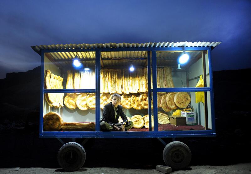 Sabor, an 11-year-old Afghan boy, sits in a bakery booth waiting for customers on the outskirts of Kabul, Afghanistan. EPA