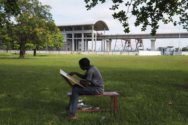 A man works on a pastel drawing in front of the National Arts Theatre stop of the light rail system under construction in Lagos. The first test runs should start in 2015, according to an official at the National Arts Theatre work site. Joe Penney / Reuters