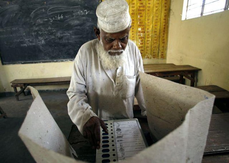 An elderly Muslim man prepares to cast his vote by using an electronic voting machine.