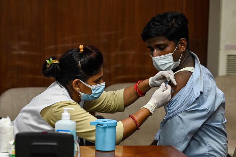 A health worker inoculates a man with a booster dose.