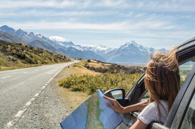 Portrait of a young woman in a car looking at a map for directions. Getty Images