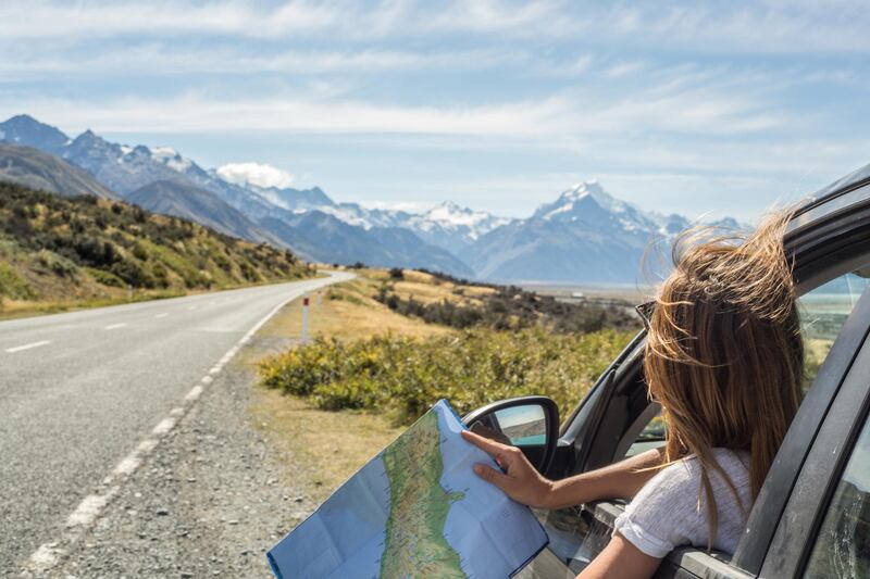 Portrait of a young woman in a car looking at a map for directions. Getty Images