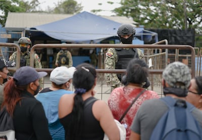 Military personnel stand guard next to family members outside the Penitenciaria del Litoral prison where prisoners were killed and injured in overnight violence.