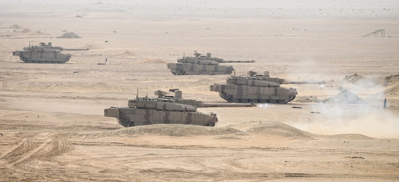 A fleet of tanks roll over the desert dunes of an Abu Dhabi training field.
