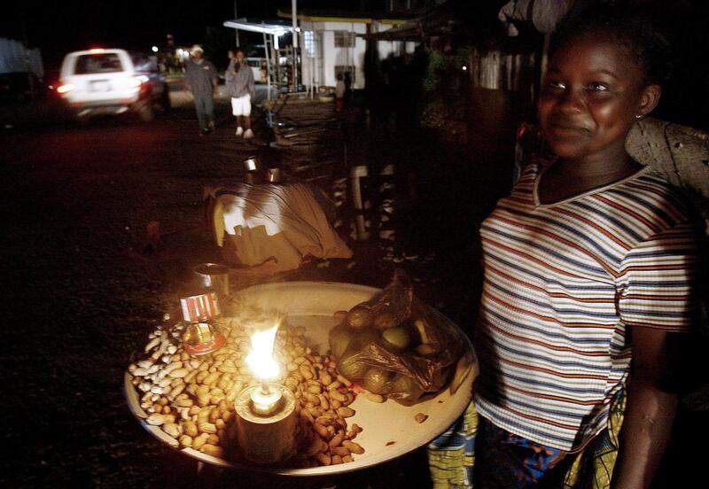 A Sierra Leonean street vendor lights her stand with a candle in Freetown. ISSOUF SANOGO / AFP