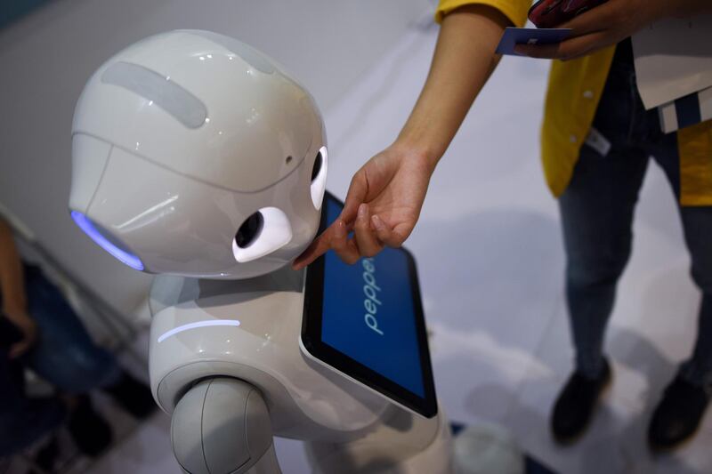 A woman touches a robot at the 2018 World Robot Conference. AFP