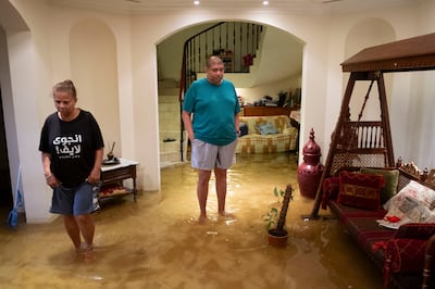 Rubesh Pillai and his wife Mallika Weerawickrama wade through floodwater at their home in Dubai's Green Community West. Antonie Robertson/The National