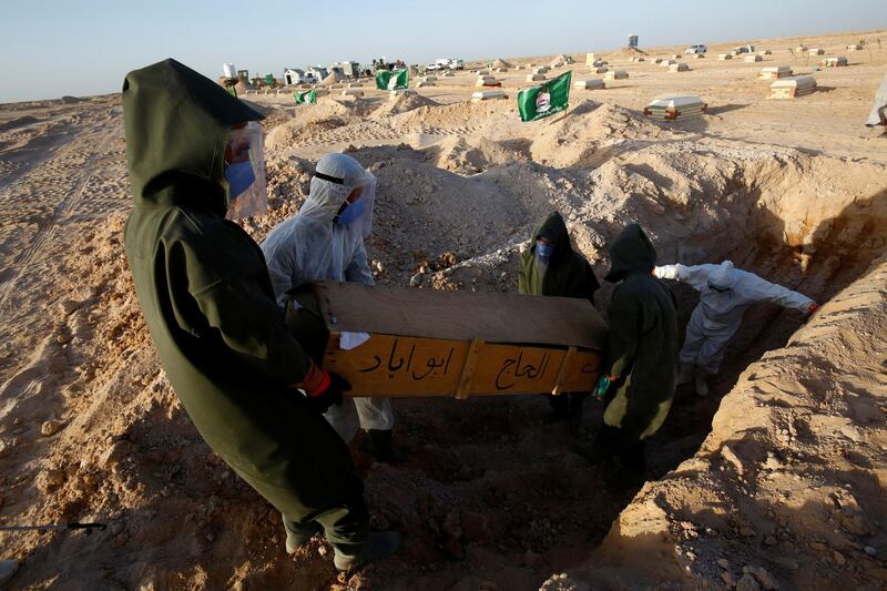 Members of the PMF, who volunteered to work at the cemetery, wear protective suits as they bury the coffin of a man who passed away due to coronavirus disease. REUTERS