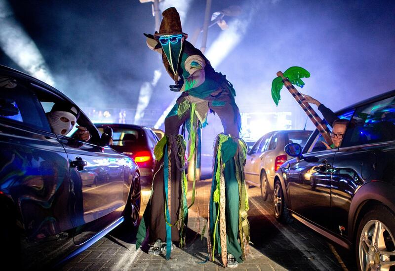 An actor walks on stilts during a car disco across the parking lot of the discotheque "Index," in Schüttorf, Germany. This is the second time that the large-capacity discotheque in Grafschaft Bentheim offers a car disco. A total of 500 guests can participate in 250 vehicles.  AP