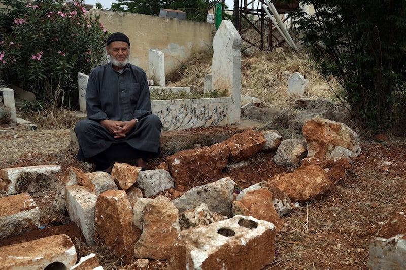 Mohammed Hassan Masto sits next to the grave of his brother Lutfi on May 7, 2023, in the village of Qorqanya, a rural area in northern Idlib province, Syria. AP
