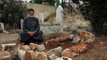 Mohammed Hassan Masto sits next to the grave of his brother Lutfi on May 7, 2023, in the village of Qorqanya, a rural area in northern Idlib province, Syria. AP