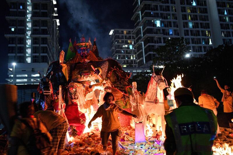 A Malaysian-Chinese devotee runs back after setting a paper statue of Chinese deity "Da Shi Ye" or the Guardian God of Ghosts, on fire to mark the Hungry Ghost Festival in Kuala Lumpur. AFP