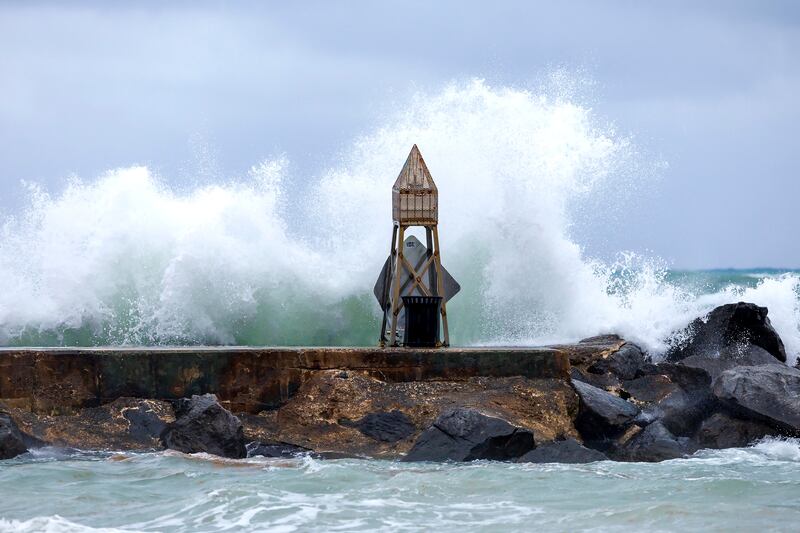 Waves crash against the jetty at the Bal Harbour Lighthouse. AP