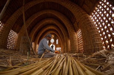 An Iraqi craftsman prepares reeds during the building of a traditional guest house or mudhif, in front of the museum of the southern city of Basra. AFP