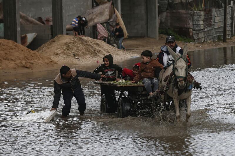 Children sit atop a donkey-pulled cart in flooded street on a rainy day in al-Amal (hope in Arabic) neighbourhood of Beit Lahia in the northern Gaza Strip.  AFP