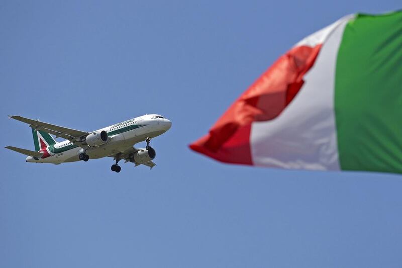 An Italy flag flutters as an Alitalia airplane approaches to land at Fiumicino airport in Rome July 31, 2014. Italy's loss-making flag carrier Alitalia is working on a final proposal to present to Etihad on Thursday in a push to lock in an investment by the Abu Dhabi-based airline, a person close to Alitalia shareholders said on Wednesday. Etihad's plans to take a 49 percent stake in Alitalia, which has made a profit only a few times in its 68-year history, has been held up by disagreements over Alitalia's 800 million euro ($1.07 billion) debt pile, and plans for job cuts that have stoked outrage among Italian unions. REUTERS/Max Rossi (ITALY - Tags: TRANSPORT BUSINESS EMPLOYMENT)