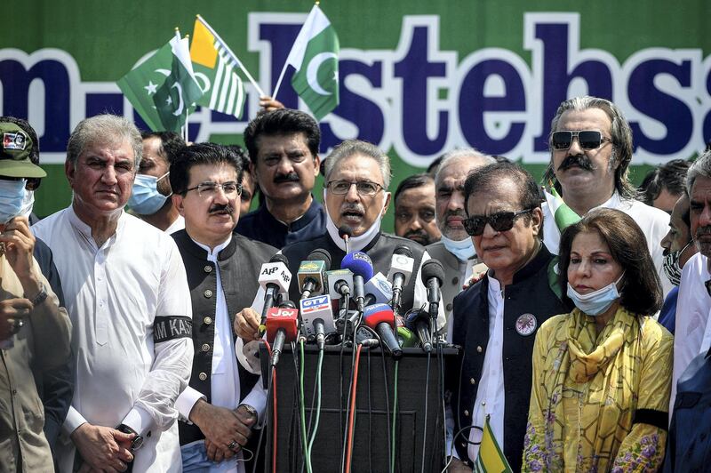 Pakistan's President Arif Alvi (C), flanked by Foreign Minister Shah Mehmood Qureshi (L) and other leaders, speaks during a rally organised to show their solidarity with people of Indian-administered Kashmir, on a street in Islamabad on August 5, 2020, to mark the one-year anniversary of the restive Kashmir region being stripped of its autonomy. - Prime Minister Narendra Modi imposed direct rule last August 5, 2019, promising peace and prosperity after three decades of violence that have seen tens of thousands of people killed in an anti-India uprising (Photo by Aamir QURESHI / AFP)