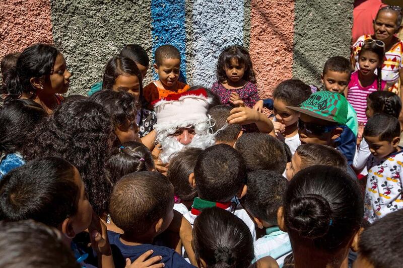 A man dressed as Santa Claus is surrounded by children as he visits a poor neighbourhood in Caracas, Venezuela. Miguel Gutierrez / EPA