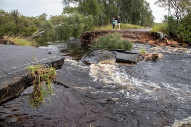 A couple stand at a washed-out section of road in Port Stephens, 200 kilometres north of Sydney, after heavy rains hit eastern Australia on March 20, 2021. AP Photo