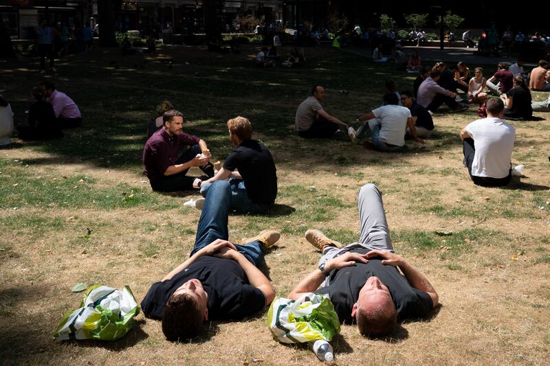 People relax in the sun in Victoria, central London. The Met Office has issued a red extreme heat warning for parts of England early next week. PA