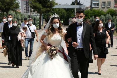 FILE PHOTO: Bride Pelsin Akkoyun and groom Nizamettin Bingol, wearing protective face masks, walk following their civil wedding ceremony, amid the spread of the coronavirus disease (COVID-19), in Diyarbakir, Turkey, July 2, 2020. Turkey reopened its wedding halls in one of the final steps of reopening from the shutdown due to the coronavirus disease (COVID-19). REUTERS/Sertac Kayar/File Photo