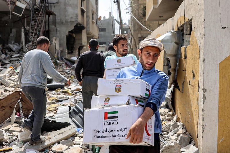 Men carry boxes of aid through the rubble of damaged buildings after the airdrop