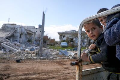 Displaced Syrian boys look towards the camera from the back of their family truck as they visit their home in the village of al-Nayrab, about 14 kilometres southeast of Idlib city and seven kilometres west of Saraqib in northwestern Syria on March 29, 2020.  / AFP / AAREF WATAD
