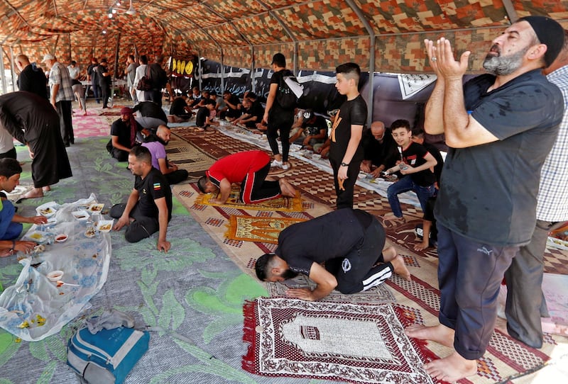 Iraqi Shiite Muslim pilgrims pray and others eat at a tent set up by volunteers to provide a place for pilgrims to rest as they walk to Kerbala, ahead of the Shiite ritual of Arbaeen.  Reuters