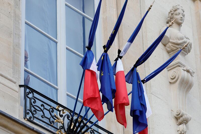 A man watches French and European flags at half-mast to pay homage to former French President Jacques Chirac, at the Elysee Palace in Paris. AP Photo
