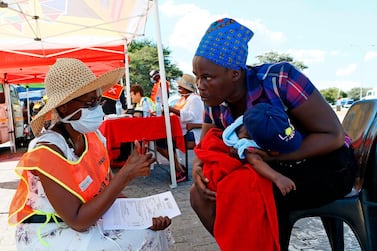 A health official gives a thumbs up after conducting a screening test on a traveller carrying a baby in South Africa. AFP