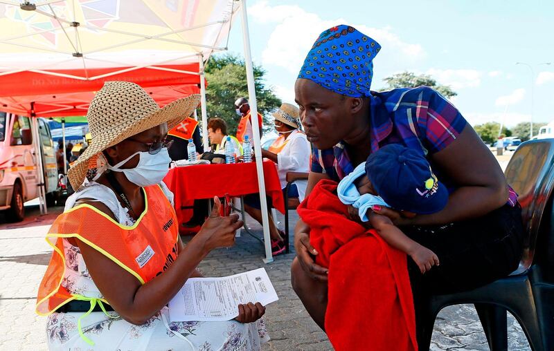 TOPSHOT - Limpopo Provincial health official gives a thumbs up after conducting a screening test on a traveller carrying a baby while making her way from Gauteng to Limpopo ahead of the nationwide lockdown at Mantsole Weighbridge near Hammanskraal on March 25, 2020.  South African President Cyril Ramaphosa on March 23, 2020 announced a 21-day national lockdown to start later this week to contain the spread of the COVID-19 coronavirus which has affected more than 400 people and ordered the military to enforce the ban. / AFP / Phill Magakoe
