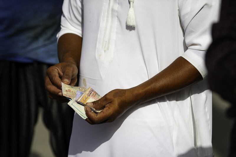 A man counts Omani riyal currency banknotes after selling fish at the Mutrah fish market in Muscat, Oman, on Monday, May 7, 2018. Being the Switzerland of the Gulf served the country well over the decades, helping the sultanate survive, thrive and make it a key conduit for trade and diplomacy in the turbulent Middle East. Photographer: Christopher Pike/Bloomberg