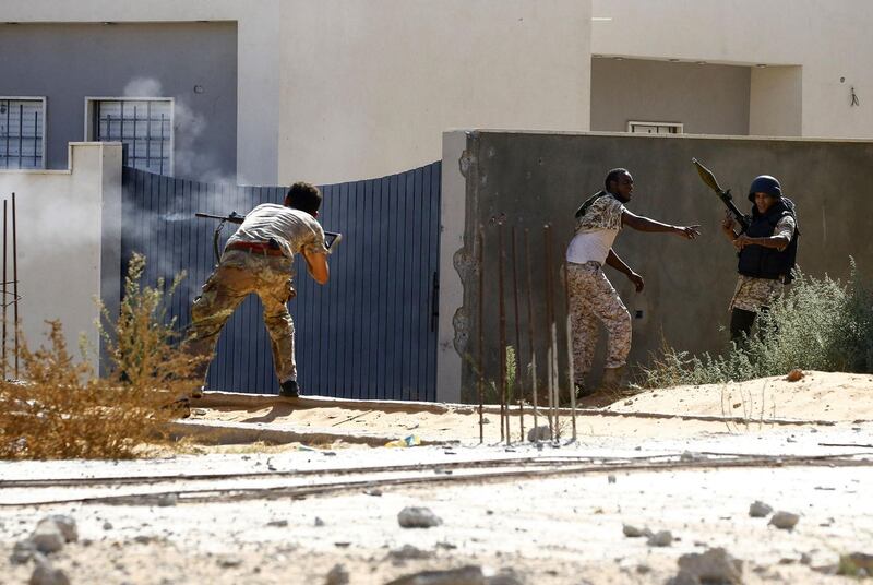 A fighters loyal to the internationally recognised Libyan Government of National Accord (GNA) shoots fires his rifle as others take position behind a wall during clashes with forces loyal to strongman Khalifa Haftar in the capital Tripoli's suburb of Ain Zara.  AFP