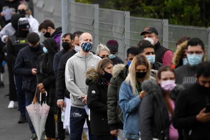 Members of the public queue to receive a Covid-19 vaccine at a temporary vaccination centre at the Essa academy in Bolton, northwest England on May 14, 2021. England remains on track for the latest easing of its coronavirus lockdown next week but is taking no chances after a doubling of cases of an Indian variant, the government said today. / AFP / Oli SCARFF
