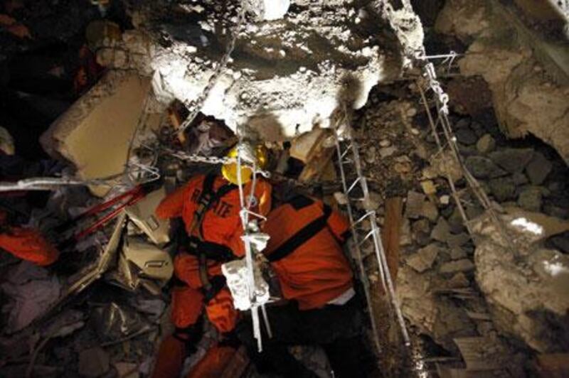 Rescuers peek under rubble to talk to trapped survivor Manuel Lora at the site of a four-storey building collapse in Port-au-Prince, Haiti, on Wednesday, January 13, 2010.