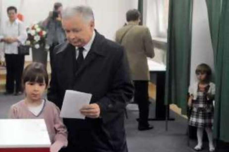 Presidential candidate Jaroslaw Kaczynski, twin brother of the late President Lech Kaczynski killed in a plane crash, prepares to cast his ballot, accompanied by his brother's grand daughters Eva, left, and Martyna, right, in the presidential election in Warsaw, Poland, Sunday, June 20, 2010. Poles are voting Sunday to choose Lech Kaczynski's successor. (AP Photo/Alik Keplicz) *** Local Caption ***  PJO108_Poland_Presidential_Election.jpg