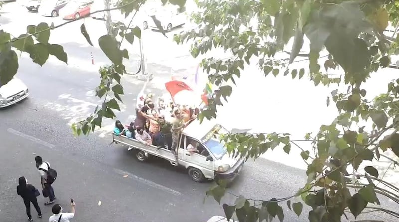 People wave flags as they ride on a vehicle in Yangon, Myanmar. Reuters