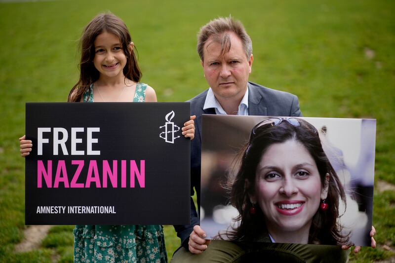 Richard Ratcliffe, the husband of imprisoned Nazanin Zaghari-Ratcliffe, and their 7-year-old daughter Gabriella hold up pictures of Nazanin in Parliament Square in London in September 2021, to mark the 2,000 days she has been detained in Iran. AP